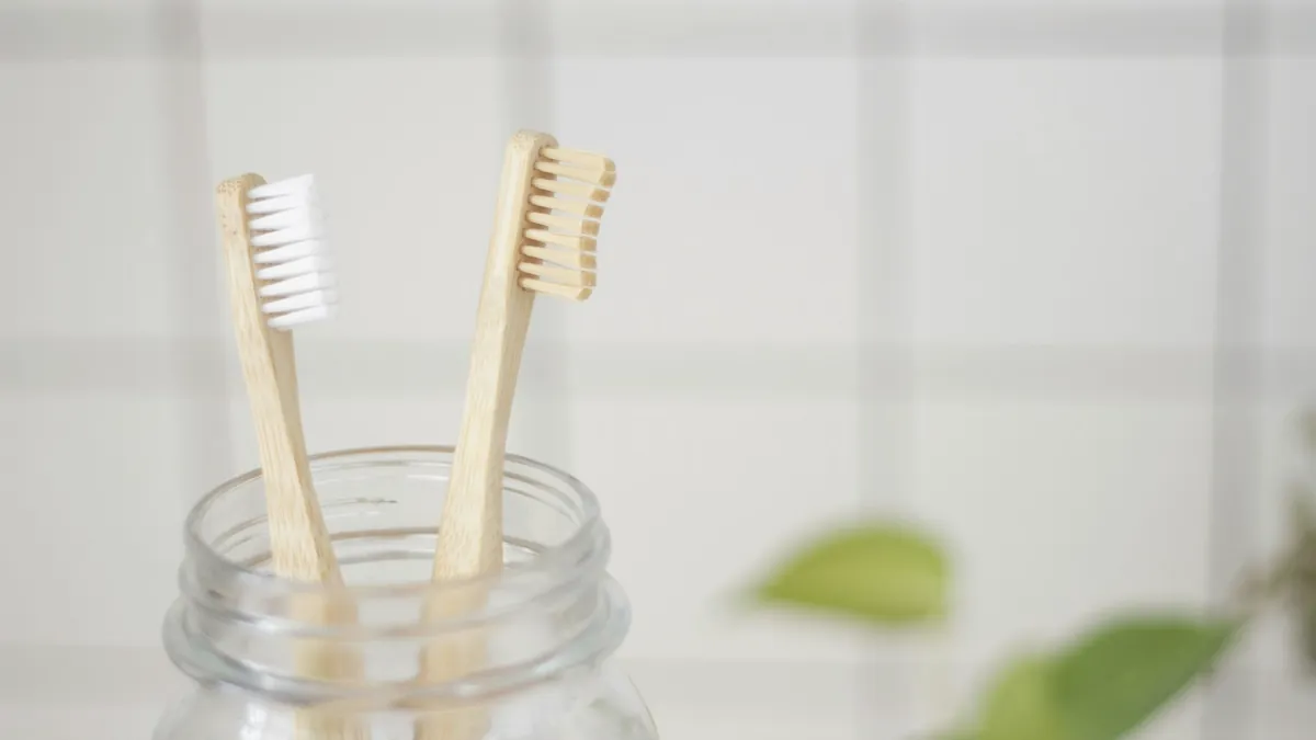 Dos cepillos de dientes de bambú en un frasco de vidrio.